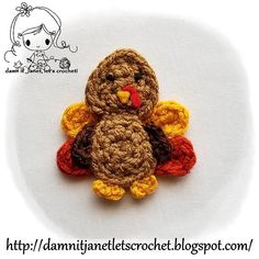 a small crocheted turkey sitting on top of a white surface with the words happy thanksgiving written below it