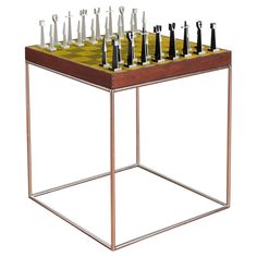 a metal and wood table with chess pieces on it's side, in front of a white background