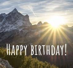 a happy birthday card with the sun shining over mountains and trees in the foreground