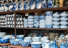 many blue and white vases are on display in a store shelf with shelves full of them