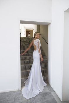 a woman in a white dress is standing on some stairs