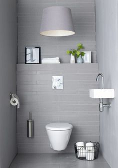 a white toilet sitting in a bathroom next to a wall mounted light above it's tank