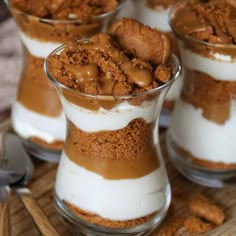 three desserts in small glass dishes on a wooden tray with spoons and utensils