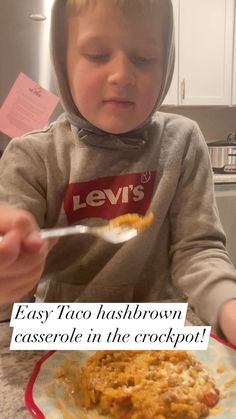 a little boy sitting in front of a plate with some food on it and the caption says, easy taco hashbrown casserole in the crockpot