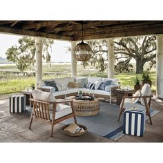 an outdoor living area with furniture and decor on the porch, including couches, chairs, tables, and rugs