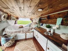 the interior of a camper with wood paneling and white furniture, including a bed