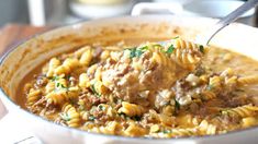 a close up of a bowl of food with pasta and meat in it on a table