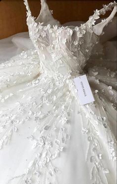 a white wedding dress is displayed on a bed