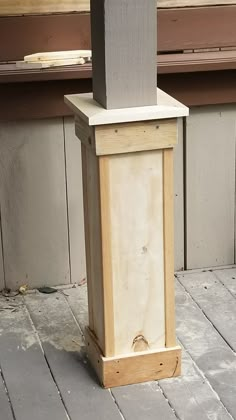 a wooden box sitting on the ground next to a window sill with a bench in the background