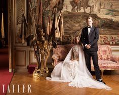 a bride and groom posing for a photo in front of a wall with paintings on it