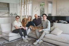 four people sitting on a couch with two dogs