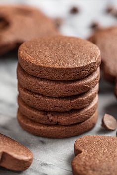 a stack of chocolate cookies sitting on top of a counter next to some pieces of chocolate