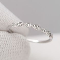 a white gold wedding ring with diamonds on it's side, sitting on top of a cloth