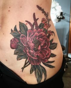 a woman's stomach with a flower tattoo on her belly and the bottom part of her lower back