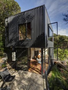 a house made out of shipping containers on the side of a hill with trees in the background