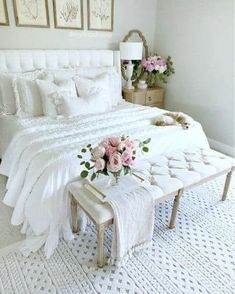 a white bed sitting in a bedroom next to a table with flowers on top of it