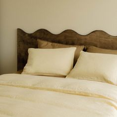 a bed with white sheets and pillows in a room