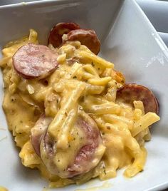 a white plate topped with pasta covered in cheese and sausages on top of it