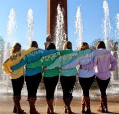 four girls are standing in front of a fountain