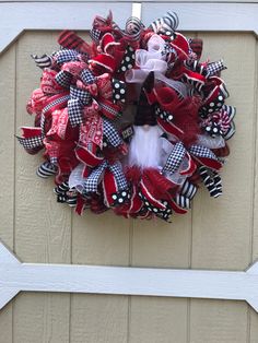 a red and black wreath hanging on the side of a door with polka dot ribbon