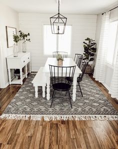 a dining room table with chairs and a rug on the floor in front of it