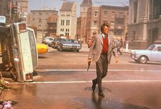 a man in a suit walking across a street with an umbrella on a rainy day