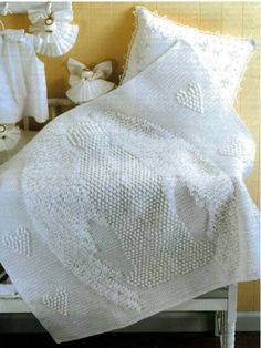 a white crocheted blanket sitting on top of a bed next to a night stand