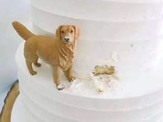 a dog figurine standing on top of a white tiered cake with frosting