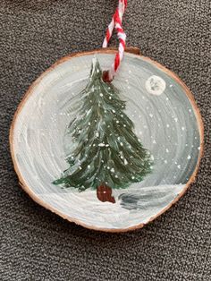 a painted christmas tree on a wood slice with candy canes in the foreground