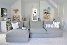 a large gray couch sitting in a living room next to a white wall and ceiling