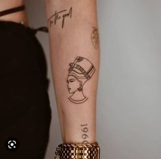 a woman's arm with tattoos on it and a gold bracelet around her wrist