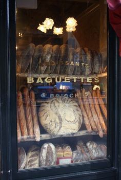 a bakery window with breads and baguettes in it