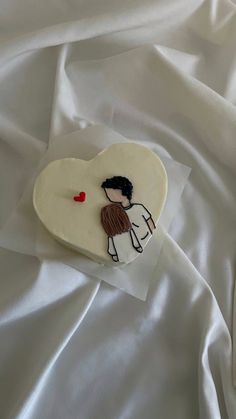 a heart shaped cookie with a drawing of a man holding a woman on it's back