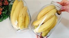 two glass jars filled with bananas sitting on top of a white counter next to a plant