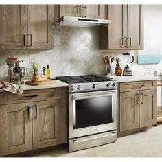 a stove top oven sitting inside of a kitchen next to wooden cupboards and counter tops