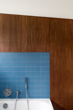 a bath tub sitting under a wooden wall next to a shower head and faucet