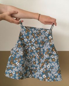 a person holding up a blue and brown flowered skirt with white flowers on it