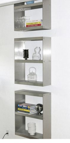 three metal shelves with books and vases on them