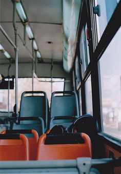 an empty bus with orange seats on the front and back sides, looking out the window