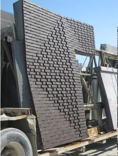 two men standing next to each other in front of a building with bricks on it