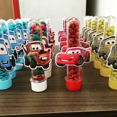 cars and trucks are on display in front of some candy cups with the characters from disney pixama