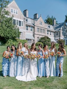 a group of women standing next to each other in front of a large building holding bouquets