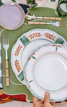 a place setting with plates and utensils on a green tableclothed cloth