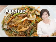 a woman holding a plate full of noodles and vegetables