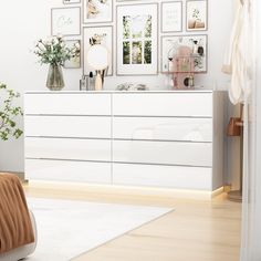 a white dresser sitting next to a bed in a room with pictures on the wall