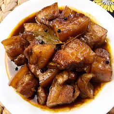 a white plate topped with meat covered in gravy and sauce on top of a woven place mat