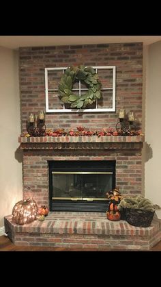 a brick fireplace with a wreath on the mantle and pumpkins in front of it