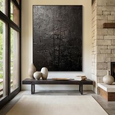 a living room with a large black painting on the wall and two white vases