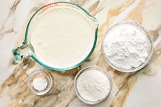 the ingredients are in small bowls on the marble counter top, including milk and flour