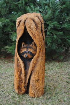 a wood carving of two raccoons in a tree stump